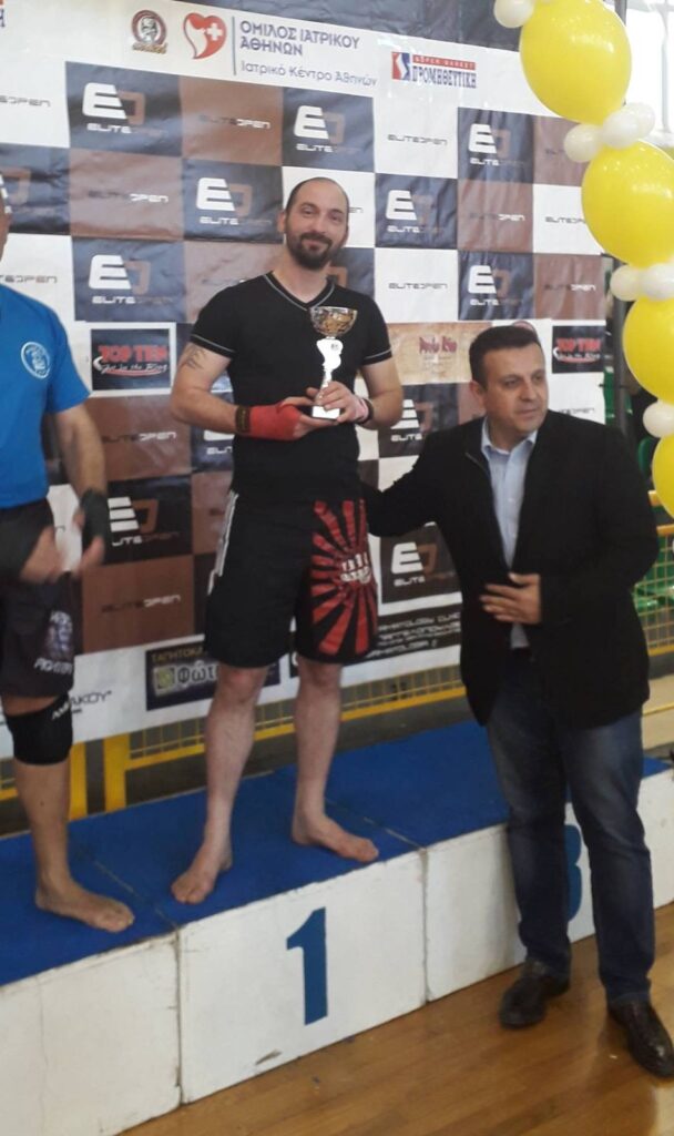 Αθλητής του Fighting Spirit στην πρώτη θέση του βάθρου με κύπελλο, διοργάνωση Elite Open